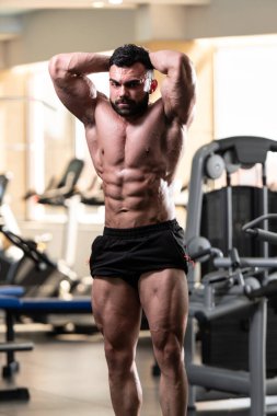 Yakışıklı Genç Adam Spor Salonunda Güçlü Duruyor ve Kaslarını Geriyor - Kas Atletik Vücut Geliştirici Spor Sonrası Spor Pozisyonu