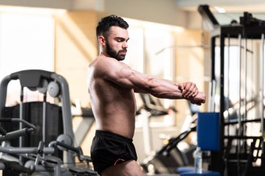 Spor salonu ve kasların esneme - güçlü ayakta sağlıklı genç adam kaslı atletik vücut Fitness Model çalışmaları sonra poz