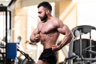 Yakışıklı Genç Adam Spor Salonunda Güçlü Duruyor ve Kaslarını Geriyor - Kas Atletik Vücut Geliştirici Spor Sonrası Spor Pozisyonu