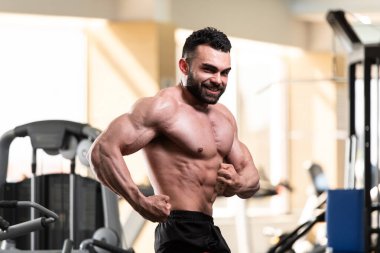 Spor salonu ve kasların esneme - güçlü ayakta sağlıklı genç adam kaslı atletik vücut Fitness Model çalışmaları sonra poz