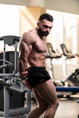 Yakışıklı Genç Adam Spor Salonunda Güçlü Duruyor ve Kaslarını Geriyor - Kas Atletik Vücut Geliştirici Spor Sonrası Spor Pozisyonu
