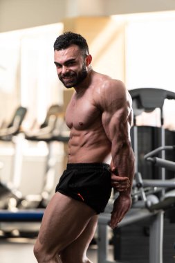 Spor salonu ve kasların esneme - güçlü ayakta sağlıklı genç adam kaslı atletik vücut Fitness Model çalışmaları sonra poz