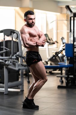 Yakışıklı Genç Adam Spor Salonunda Güçlü Duruyor ve Kaslarını Geriyor - Kas Atletik Vücut Geliştirici Spor Sonrası Spor Pozisyonu