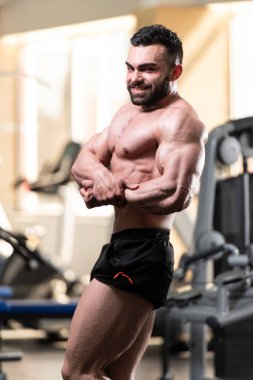 Spor salonu ve kasların esneme - güçlü ayakta sağlıklı genç adam kaslı atletik vücut Fitness Model çalışmaları sonra poz