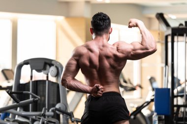 Yakışıklı Genç Adam Spor Salonunda Güçlü Duruyor ve Kaslarını Geriyor - Kas Atletik Vücut Geliştirici Spor Sonrası Spor Pozisyonu