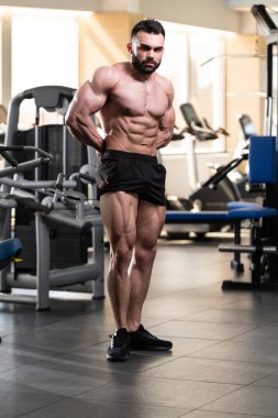 Yakışıklı Genç Adam Spor Salonunda Güçlü Duruyor ve Kaslarını Geriyor - Kas Atletik Vücut Geliştirici Spor Sonrası Spor Pozisyonu