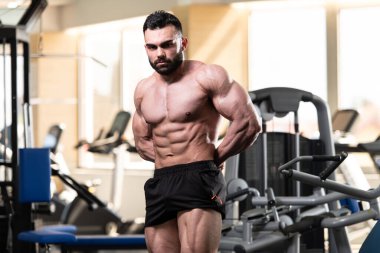 Spor salonu ve kasların esneme - güçlü ayakta sağlıklı genç adam kaslı atletik vücut Fitness Model çalışmaları sonra poz
