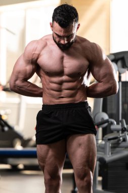 Spor salonu ve kasların esneme - güçlü ayakta sağlıklı genç adam kaslı atletik vücut Fitness Model çalışmaları sonra poz