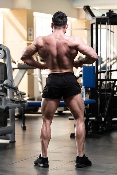 Spor salonu ve kasların esneme - güçlü ayakta sağlıklı genç adam kaslı atletik vücut Fitness Model çalışmaları sonra poz