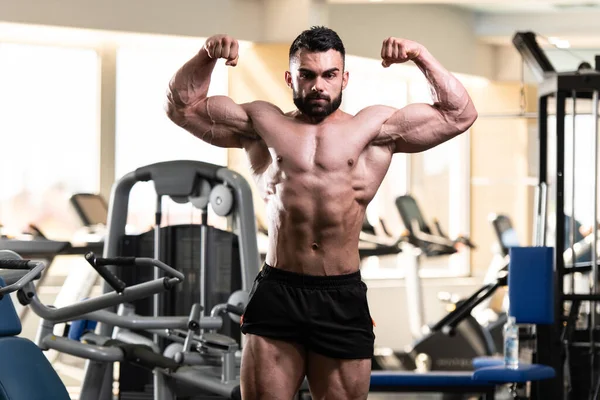 Spor salonu ve kasların esneme - güçlü ayakta sağlıklı genç adam kaslı atletik vücut Fitness Model çalışmaları sonra poz