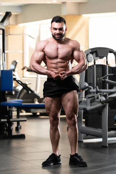 Yakışıklı Genç Adam Spor Salonunda Güçlü Duruyor ve Kaslarını Geriyor - Kas Atletik Vücut Geliştirici Spor Sonrası Spor Pozisyonu