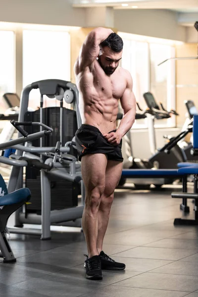 Spor salonu ve kasların esneme - güçlü ayakta sağlıklı genç adam kaslı atletik vücut Fitness Model çalışmaları sonra poz