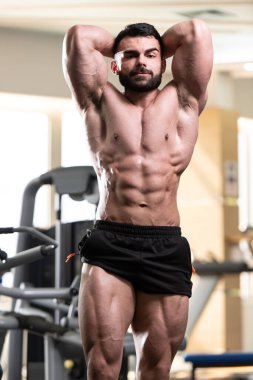 Yakışıklı Genç Adam Spor Salonunda Güçlü Duruyor ve Kaslarını Geriyor - Kas Atletik Vücut Geliştirici Spor Sonrası Spor Pozisyonu