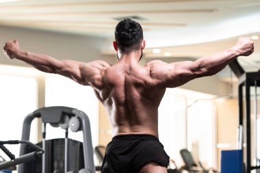 Yakışıklı Genç Adam Spor Salonunda Güçlü Duruyor ve Kaslarını Geriyor - Kas Atletik Vücut Geliştirici Spor Sonrası Spor Pozisyonu