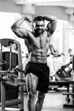 Spor salonu ve kasların esneme - güçlü ayakta sağlıklı genç adam kaslı atletik vücut Fitness Model çalışmaları sonra poz
