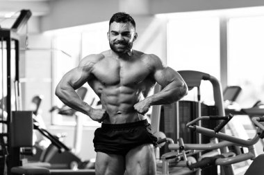 Yakışıklı Genç Adam Spor Salonunda Güçlü Duruyor ve Kaslarını Geriyor - Kas Atletik Vücut Geliştirici Spor Sonrası Spor Pozisyonu