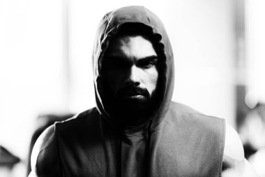 İyi eğitilmiş vücudunu kapüşonlu gösteren genç bir adamın portresi. Egzersizden sonra kaslı atletik vücut geliştirici spor modeli pozu.