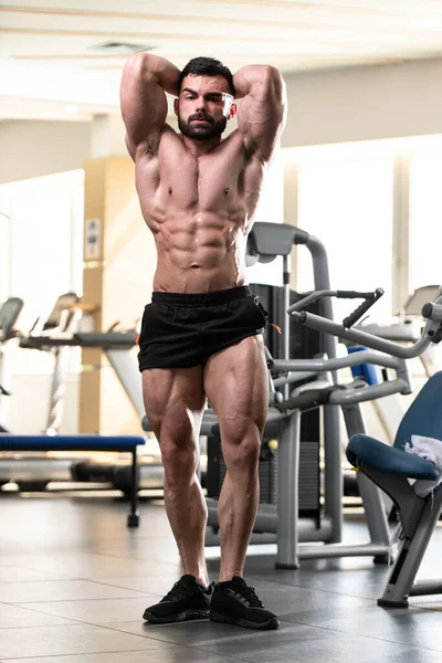 Spor salonu ve kasların esneme - güçlü ayakta sağlıklı genç adam kaslı atletik vücut Fitness Model çalışmaları sonra poz