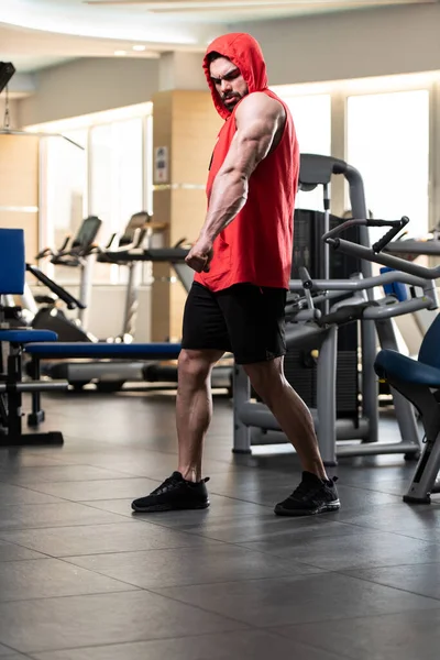 İyi eğitilmiş vücudunu kırmızı kapüşonlu gösteren genç bir adamın portresi. Egzersizden sonra kaslı atletik vücut geliştirici spor modeli pozu.