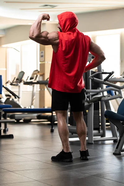 Jongeman Staat Sterk Sportschool Flexende Spieren Een Rode Hoodie Muscular — Stockfoto