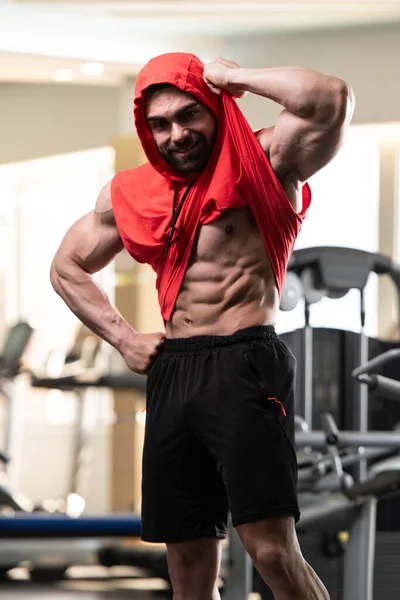 Gezonde Jongeman Staat Sterk Gym Flexing Spieren Een Rode Hoodie — Stockfoto