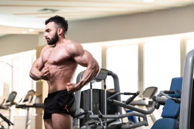 Spor salonu ve kasların esneme - güçlü ayakta sağlıklı genç adam kaslı atletik vücut Fitness Model çalışmaları sonra poz