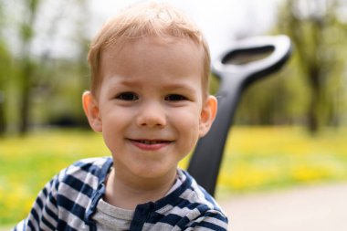 Boy Is Playing With a Toy Car Outdoors in the Park - A Happy Boy Rides in a Blue Toy Car on the Street