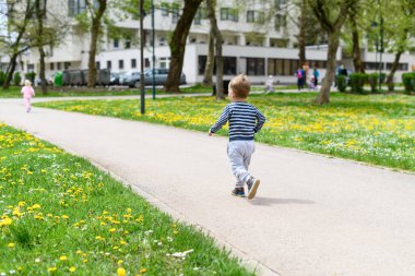 Mutlu küçük çocuk parkta eğleniyor ve koşuyor - aktif çocuk yazın açık havada eğleniyor