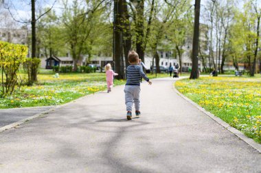 Mutlu küçük çocuklar parkta oynayıp koşmanın tadını çıkarıyorlar - Aktif oğlan ve kız yazın açık havada eğleniyorlar