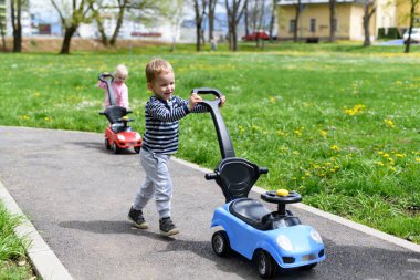 Çocuklar Parkta Oyuncak Arabayla Oynuyor - Mutlu Bir Oğlan ve Kız Caddede Mavi ve Kırmızı Oyuncak Arabayla Geziniyor