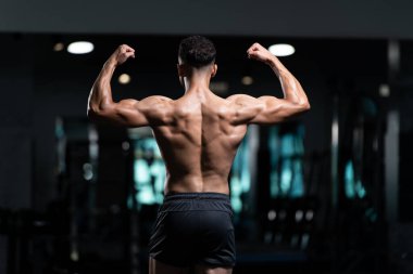 İyi eğitilmiş vücudunu gösteren genç bir adamın portresi - kaslı atletik vücut geliştirici spor sonrası vücut geliştirme modelliği pozu