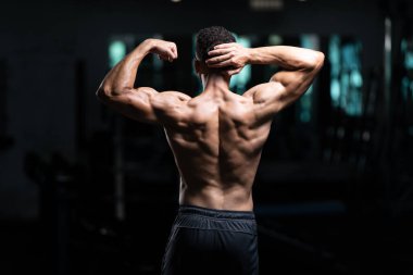 Yakışıklı Genç Adam Spor Salonunda Güçlü Duruyor ve Kaslarını Geriyor - Kas Atletik Vücut Geliştirici Spor Sonrası Spor Pozisyonu