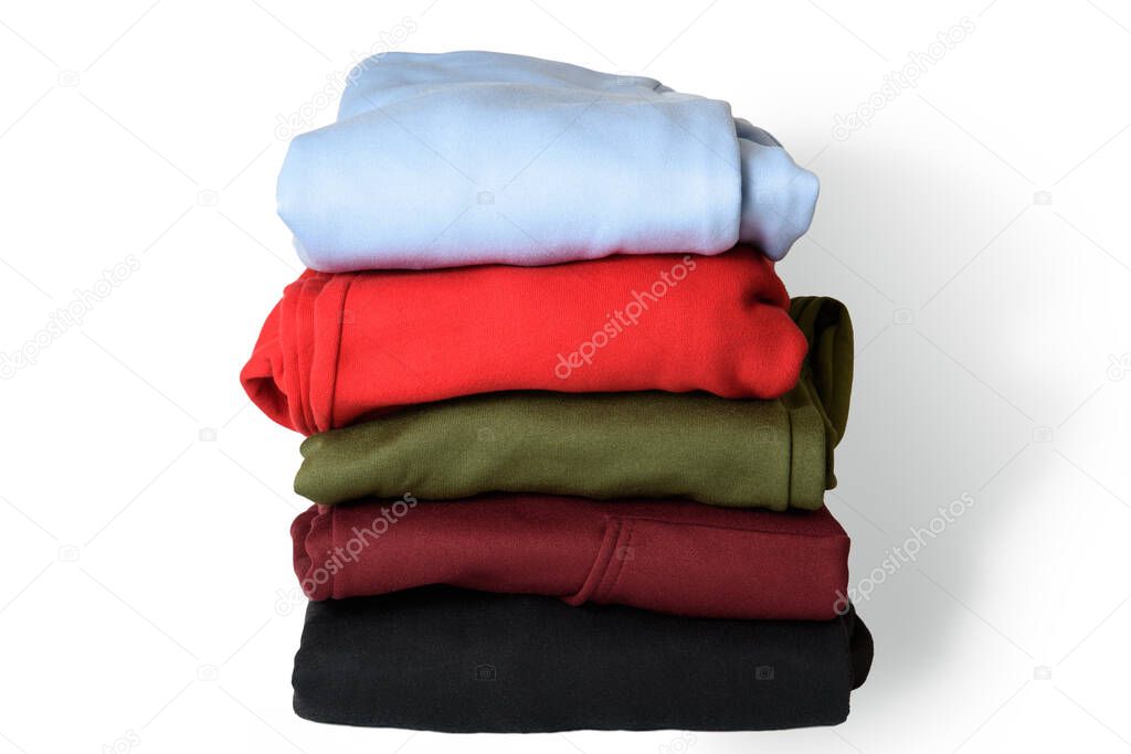Stack of folded hoodie and hooded sweatshirts on white background. Trendy comfortable casual clothes. Closeup
