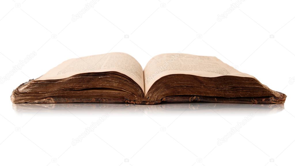 Single old worn jewish book. Open pages of Torah isolated on white background with reflection. Closeup. Selective focus