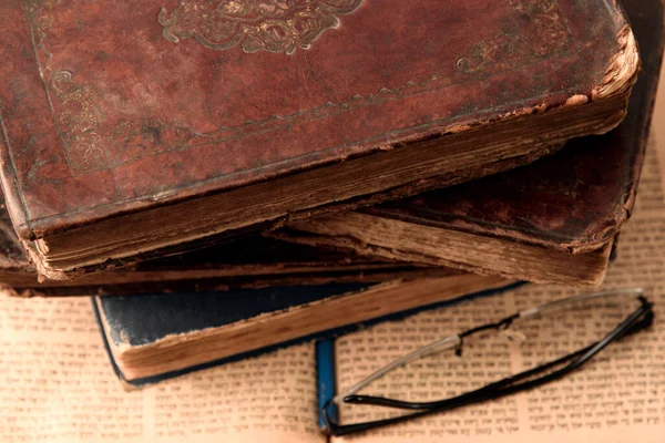 Old worn shabby leather-bound jewish books on open blurred Torah in the background. Closeup. Selective focus