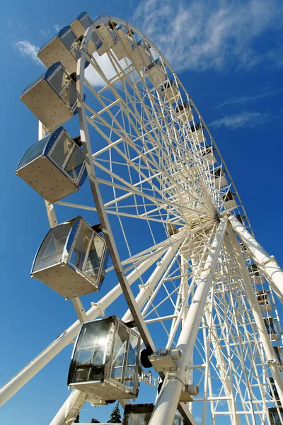 Ferris wheel against blue sky. Modern white ferris wheel. Bottom view