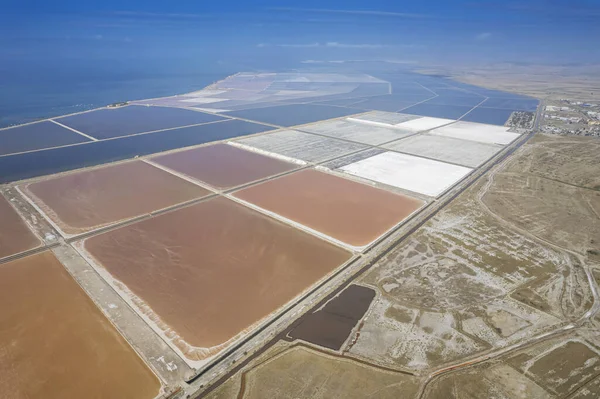 Aerial drone top view of natural sea salt ponds. Farm field outdoor. Material in traditional industry. Salt for industrial use loading in truck by labours.