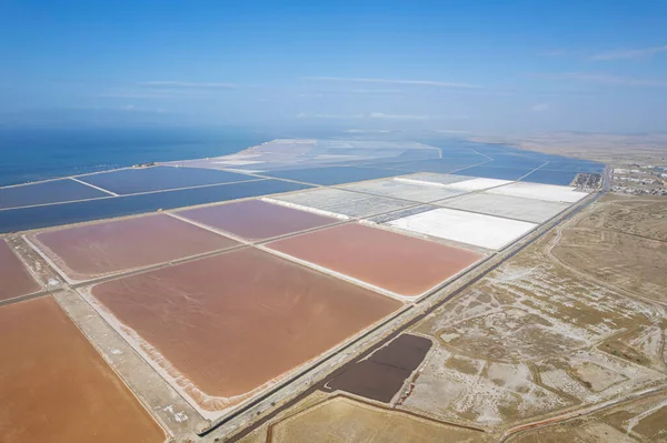 Aerial drone top view of natural sea salt ponds. Farm field outdoor. Material in traditional industry. Salt for industrial use loading in truck by labours.