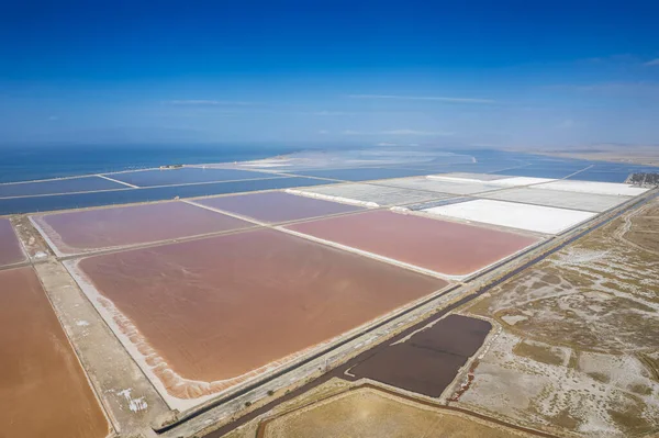 Aerial drone top view of natural sea salt ponds. Farm field outdoor. Material in traditional industry. Salt for industrial use loading in truck by labours.