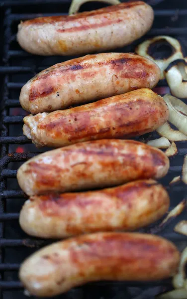 Sausages on grill with onions — Stock Photo, Image