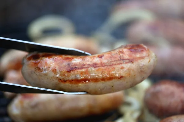 Свиная колбаса на гриле и щипцы для барбекю — стоковое фото