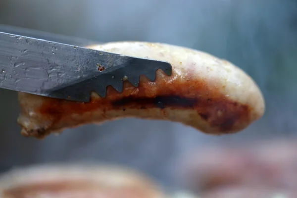 Uma pinça de churrasco com sausege close-up — Fotografia de Stock