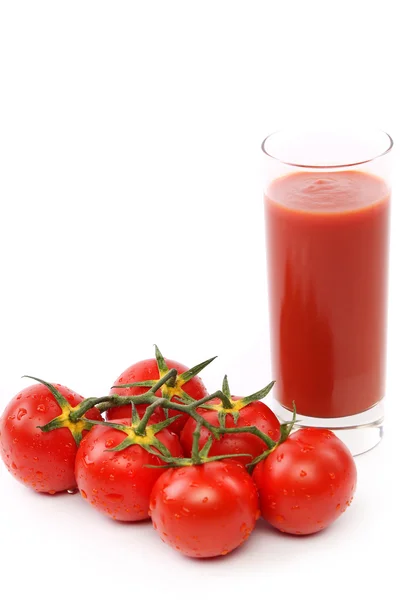 Tomato juice in glass with a cluster of tomatoes — Stock Photo, Image