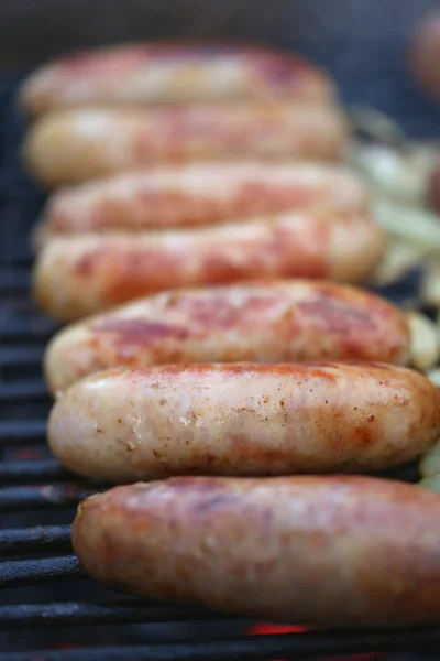 Sausages on grill with onions — Stock Photo, Image