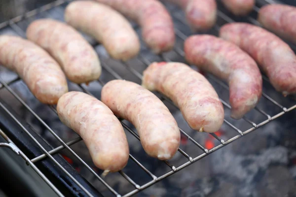 Fresh sausage grilling on a barbecue grill. — Stock Photo, Image