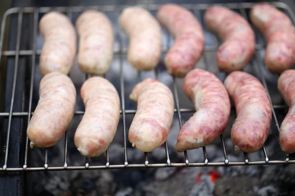 Fresh sausage grilling on a barbecue grill. — Stock Photo, Image