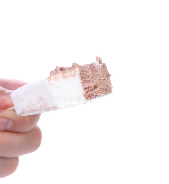 Hand holds bitten vanilla and chocolate ice cream. — Stock Photo, Image