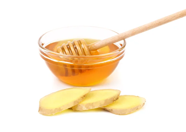 Miel dans un bol et une racine de gingembre tranches . — Photo