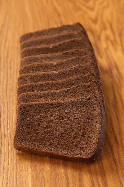 Slices of brown bread on a wooden table — Stock Photo, Image