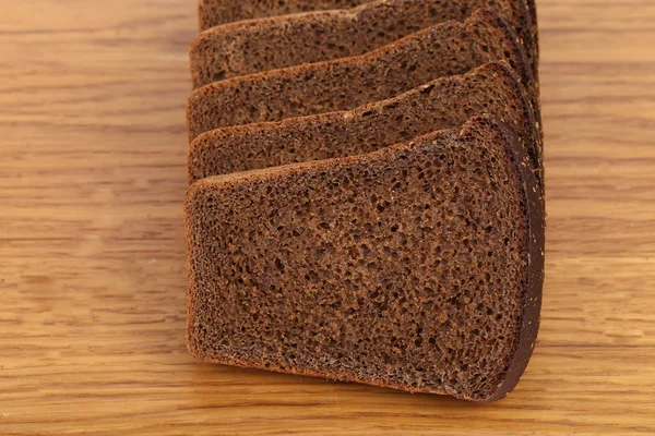 Slices of brown bread on a wooden table. — Stock Photo, Image